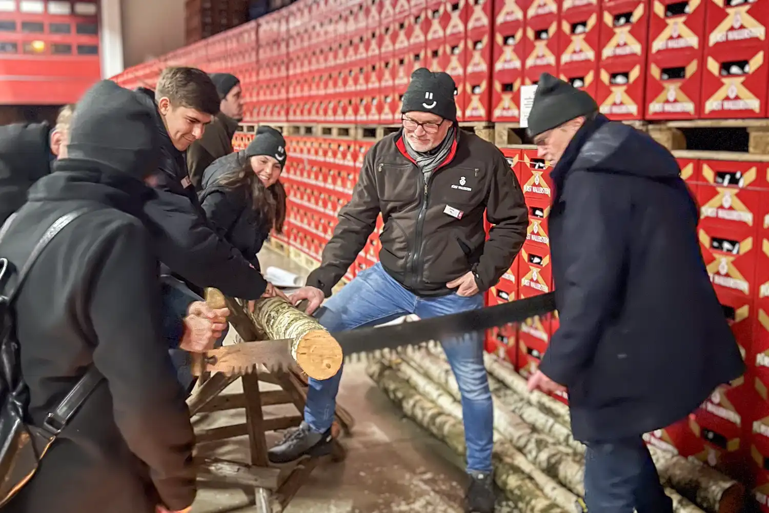 Menschen beim Baumsäge-Wettbewerb im Getränkelager bei Getränke König